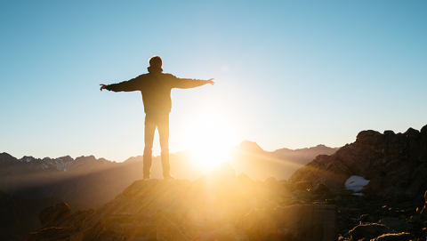 Hiker with arms stretched out looking at sunset