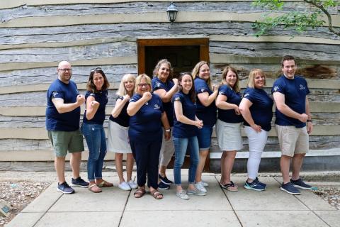 ACE Principal Academy Fellows in a line with their right sleeves rolled up flexing their arms to the camera