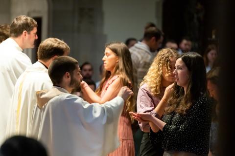 ACE teacher receiving communion from Fr. Geoffrey Mooney, CSC